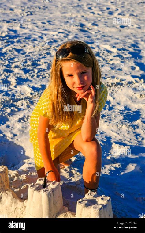 Young girl posing at sunset by the sand castle she built on Siesta Key ...