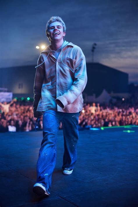 a man walking across a stage in front of an audience at a music festival with headphones on