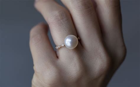 a woman's hand with a pearl ring on it