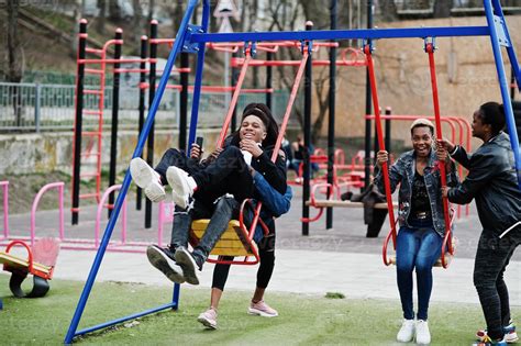 Young millennials african friends on playground, slide and swing. Happy black people having fun ...