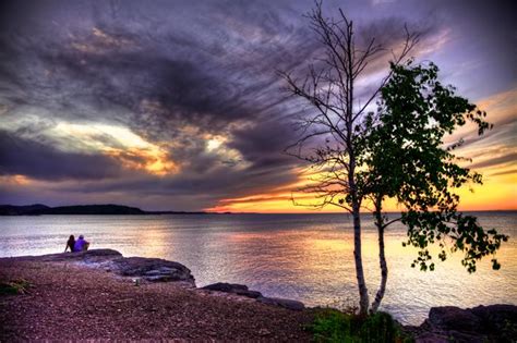 A couple watches the sunset at Presque Isle Park in Marquette, Michigan ...