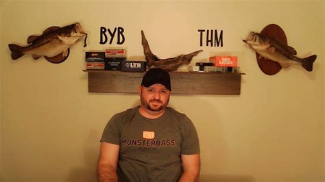 a man standing in front of three fish mounted on the wall above him is a sign that says byb tim