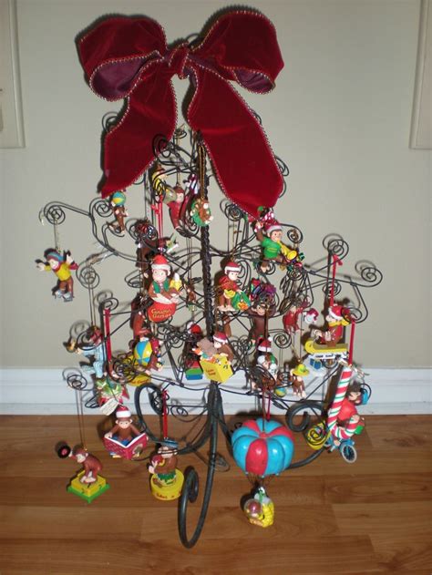 a christmas tree with lots of ornaments on it's sides and a red bow hanging from the top