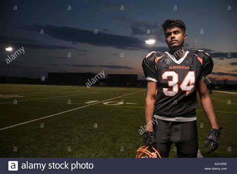 Portrait serious, tough teenage boy high school football player on football field at night Stock ...