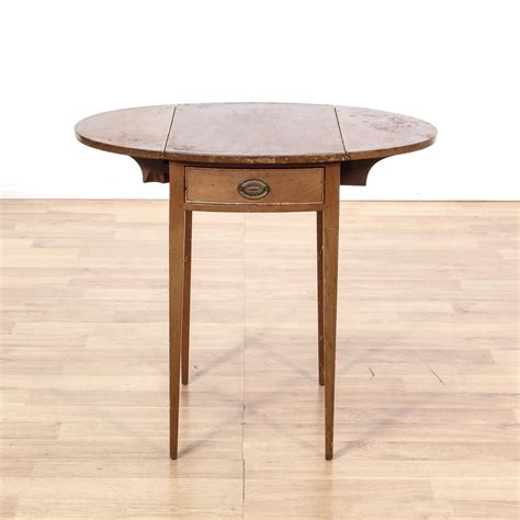 This antique drop leaf end table is featured in a solid wood with a distressed oak finish. This ...