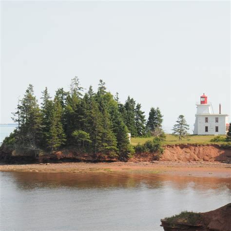 an island with a light house on top of it and trees in the foreground