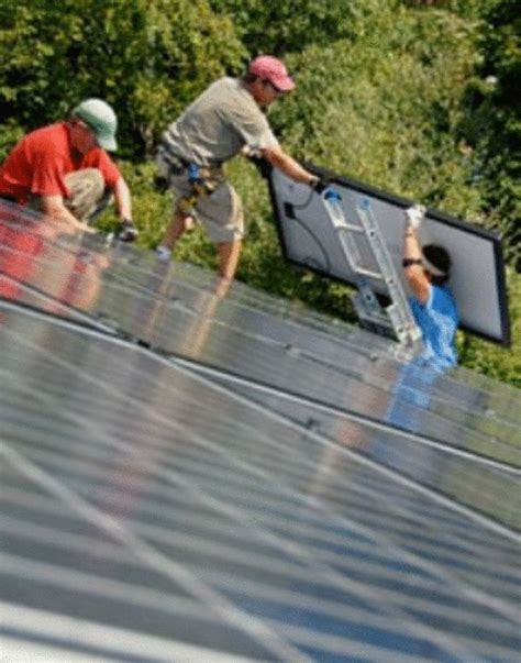 three men working on the roof of a house with solar panels and trees in the background