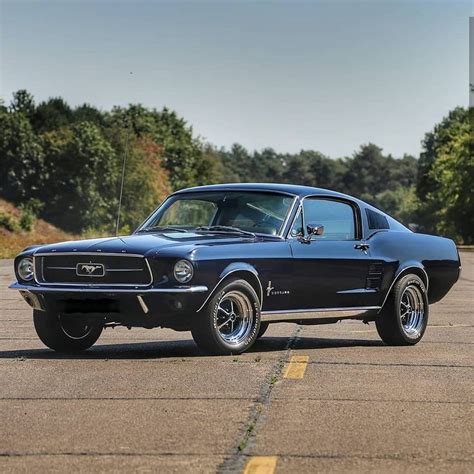 an old black mustang sitting on top of a parking lot