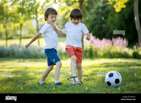 Two cute little kids, playing football together, summertime. Children ...