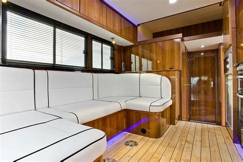 the inside of a motor home with wood flooring and white leather couches on it