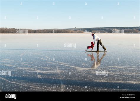 Mother and child having fun on lake ice with a traditional nordic kicksled, Lohja, southern ...