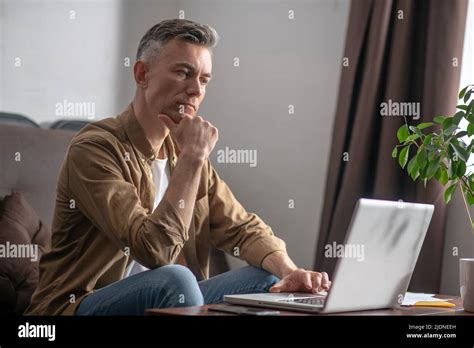 Man looking thoughtfully at laptop screen Stock Photo - Alamy