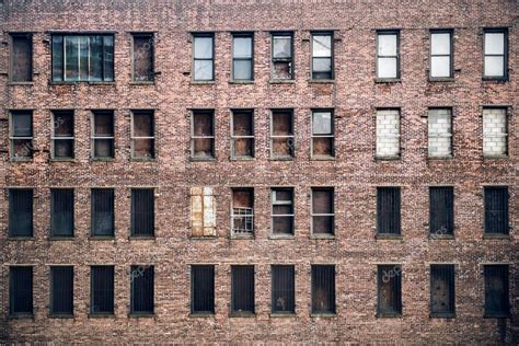 Front view of a boarded-up abandoned brick skyscraper building windows ...