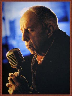 an older man holding a microphone in his hands