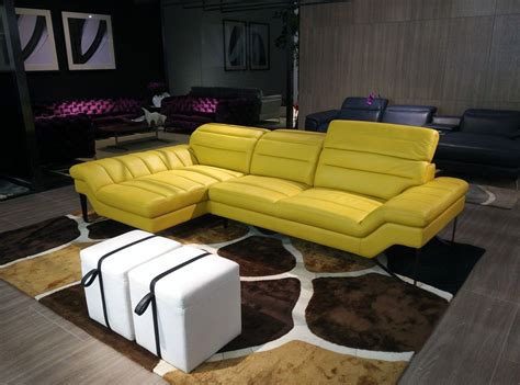 a yellow leather couch sitting on top of a brown and white rug in a living room