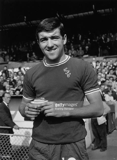 an old photo of a man holding a cup in front of a stadium full of people