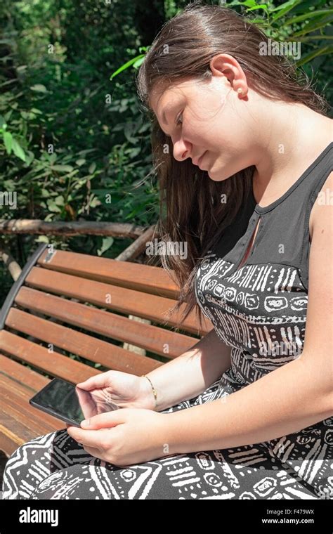 girl sitting on a bench reading to tablet Stock Photo - Alamy