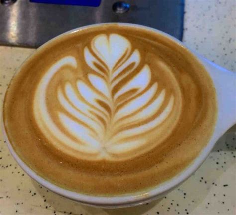 a cappuccino in a white cup with a leaf design on the top