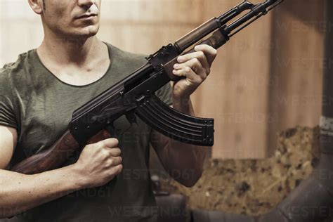 Close-up of man holding a rifle in an indoor shooting range stock photo