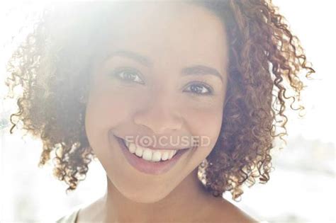 Woman with curly hair smiling at camera — female, indoor scene - Stock ...