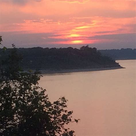 the sun is setting over some water and trees