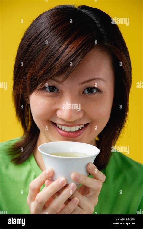 Young woman holding Chinese tea cup, smiling at camera Stock Photo - Alamy