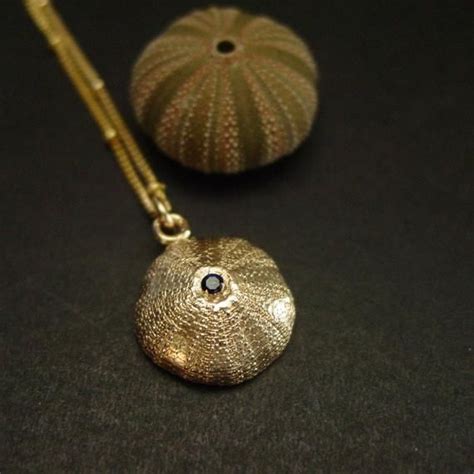 Handmade sea urchin necklace with embedded sapphire.Handmade solid yellow bronze, also called ...