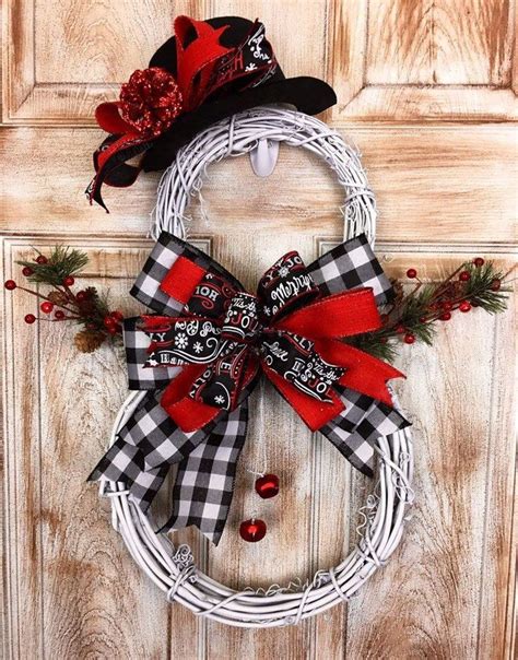 a white wreath with black and red decorations hanging on the front door, next to a wooden door