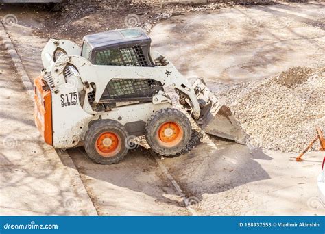 Utility Tractor Mini Loader Bobcat S175 Rakes Gravel during Repair of Asphalt on a City Street ...