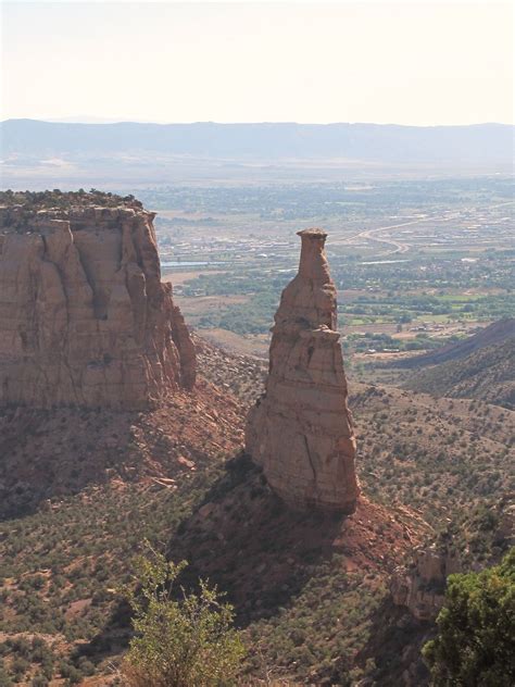 two large rocks in the middle of a desert area with mountains and valleys behind them