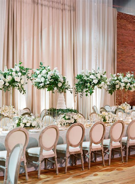 grand head table at wedding reception featured tall centerpieces of all white flowers on ...