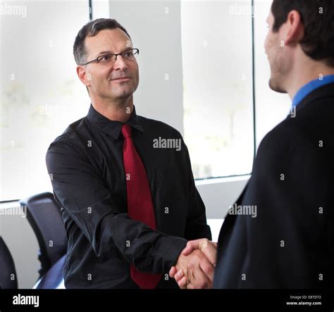 Businessmen shaking hands in office Stock Photo - Alamy