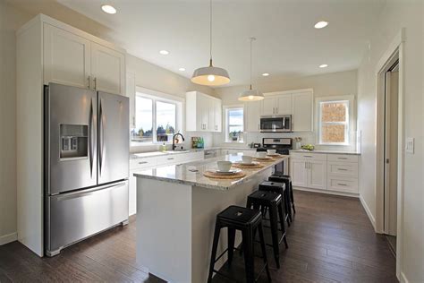 White l-shaped kitchen with shaker cabinets, engineered wood flooring, granite countertops ...