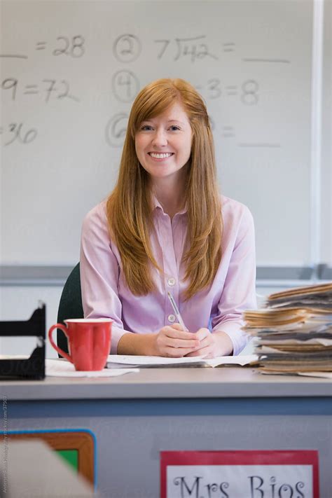 "Portrait Of Smiling Teacher Sitting At Desk In Classroom" by Stocksy ...