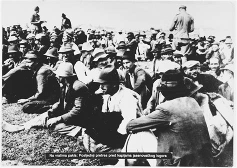 Ustasa guards move among a large group of Serbian villagers who are seated on the ground near ...