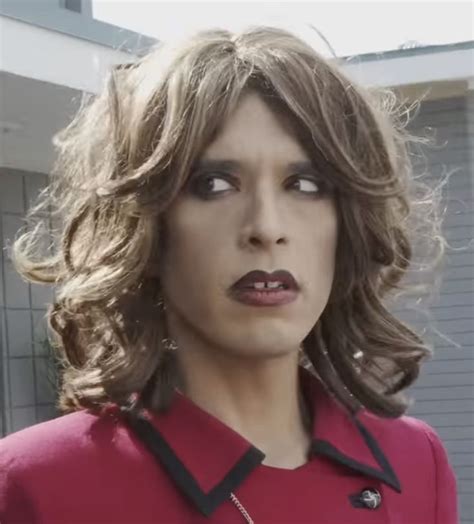 a woman in a red shirt and black collared top with her mouth open looking at the camera