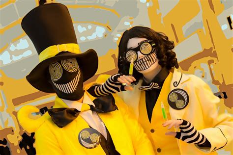 two people dressed in yellow and black are standing next to each other with masks on their faces