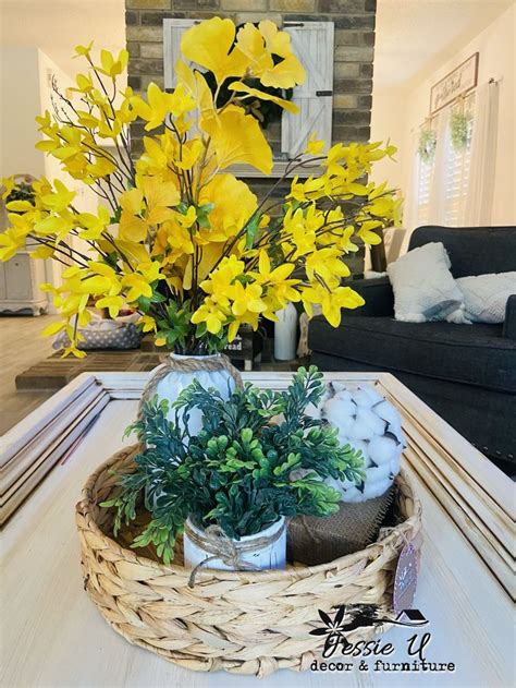 a wicker basket filled with yellow flowers on top of a white table next to a couch