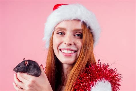 Happy Redhead Ginger Woman Wearing Santa Claus Hat and Hugging Cute Black Rat in Studio Pink ...