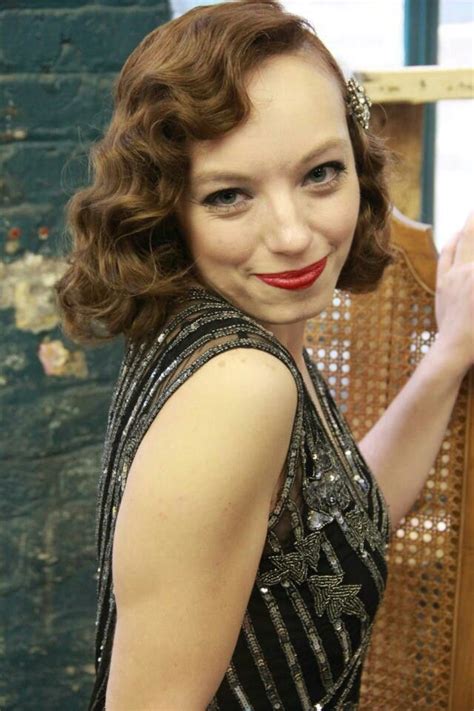 a woman in a black and silver dress holding up a brown chair with red lipstick on it