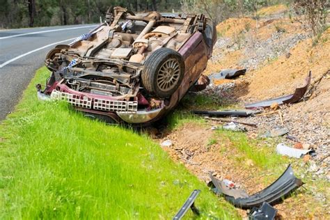 Image of Crashed car upside down on side of country road - Austockphoto