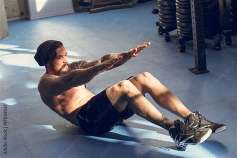 Handsome muscular man doing sit-ups on gym floor Stock Photo | Adobe Stock