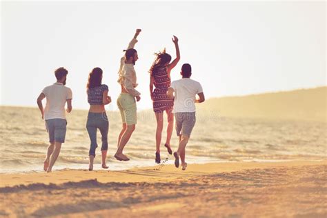 Happy Young People Group Have Fun White Running and Jumping on Beacz at Sunset Time Stock Image ...