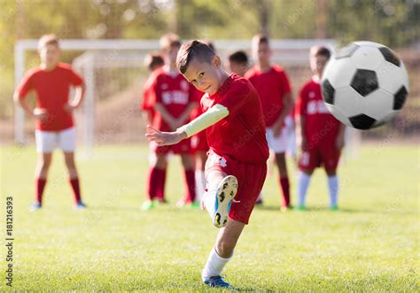 Boy kicking football on the sports field Stock Photo | Adobe Stock