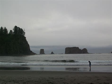 a person standing on top of a beach next to the ocean under a cloudy sky