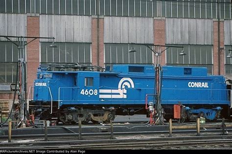 a blue train sitting on the tracks in front of a building