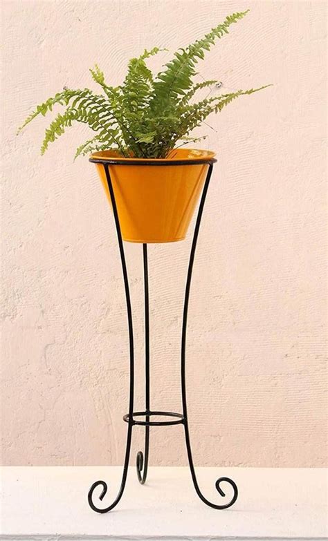 a potted plant sitting on top of a metal stand next to a white wall