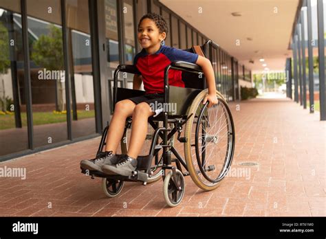 Happy disabled schoolboy sitting on wheelchair in corridor Stock Photo ...