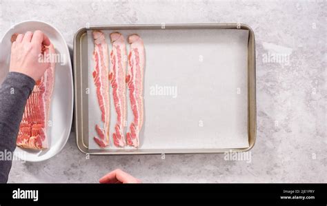 Flat lay. Step by step. Uncooked bacon strips on a baking sheet with white parchment paper Stock ...
