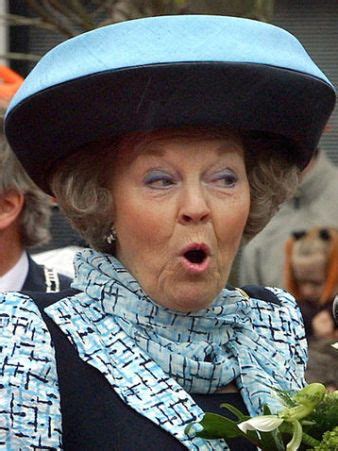 an older woman wearing a blue hat and scarf with flowers in her hand ...